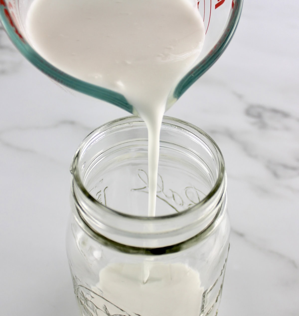 coconut milk being poured into mason jar