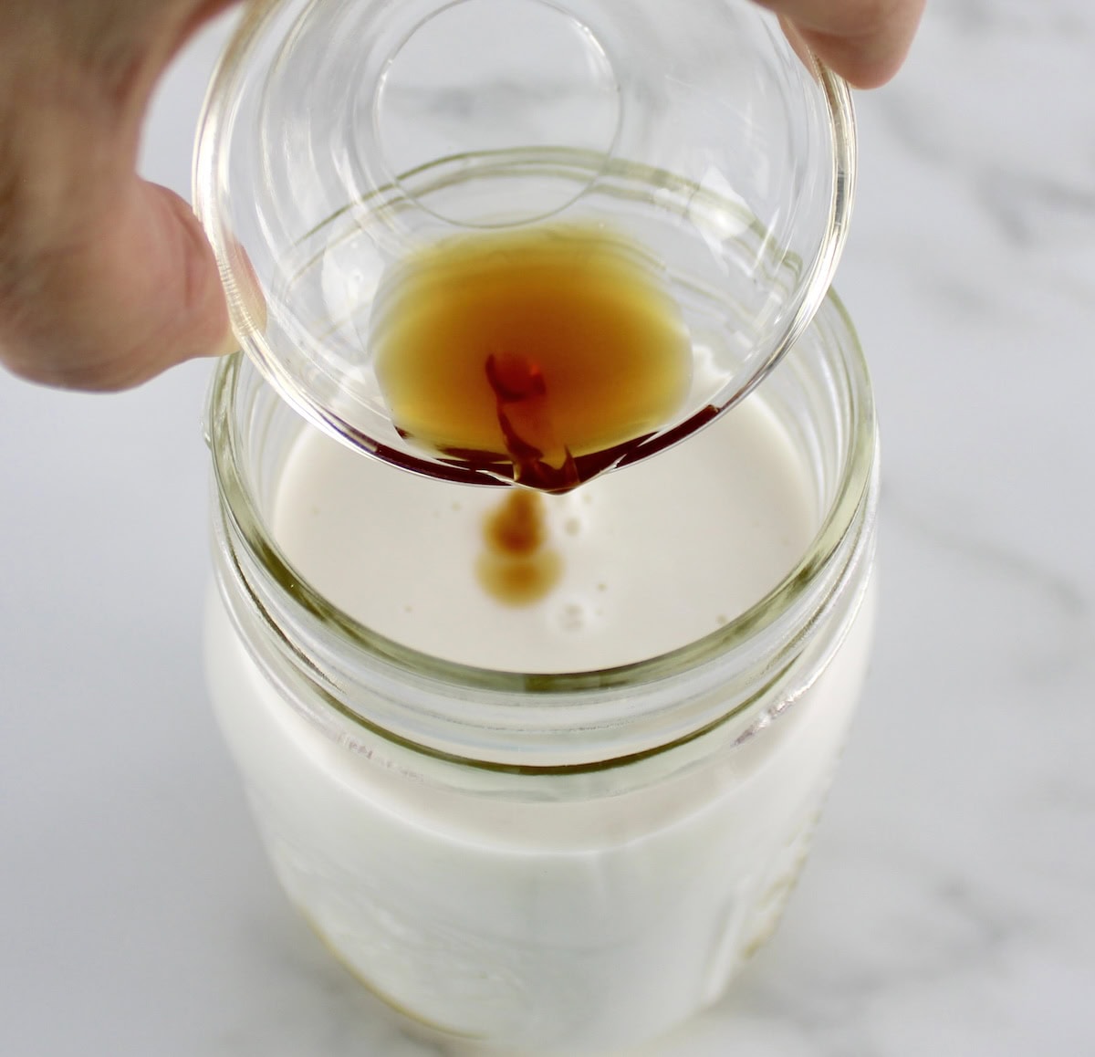 vanilla being poured into mason jar with coconut milk