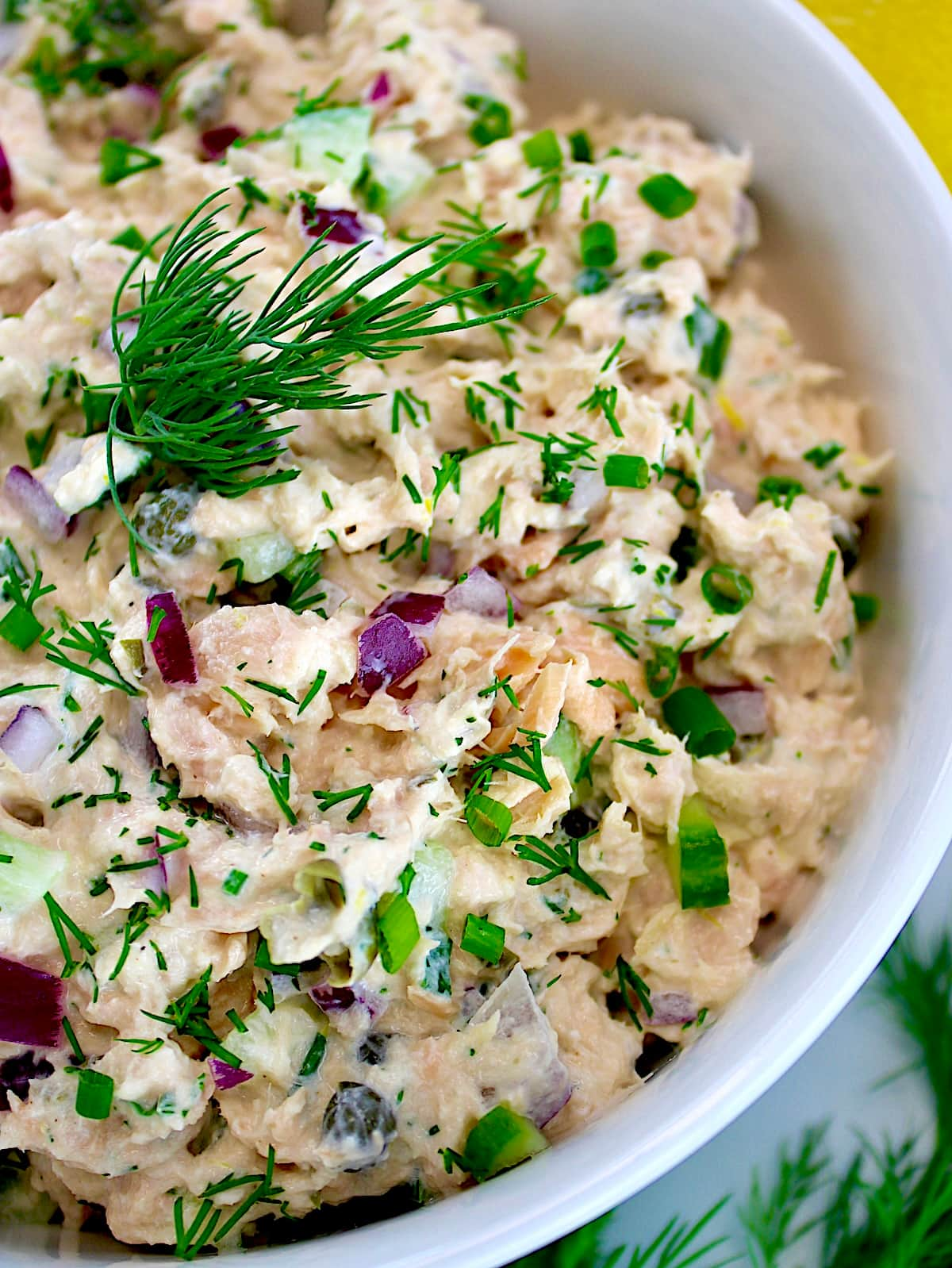 closeup of Creamy Dill Salmon Salad in white bowl with dill sprig on top