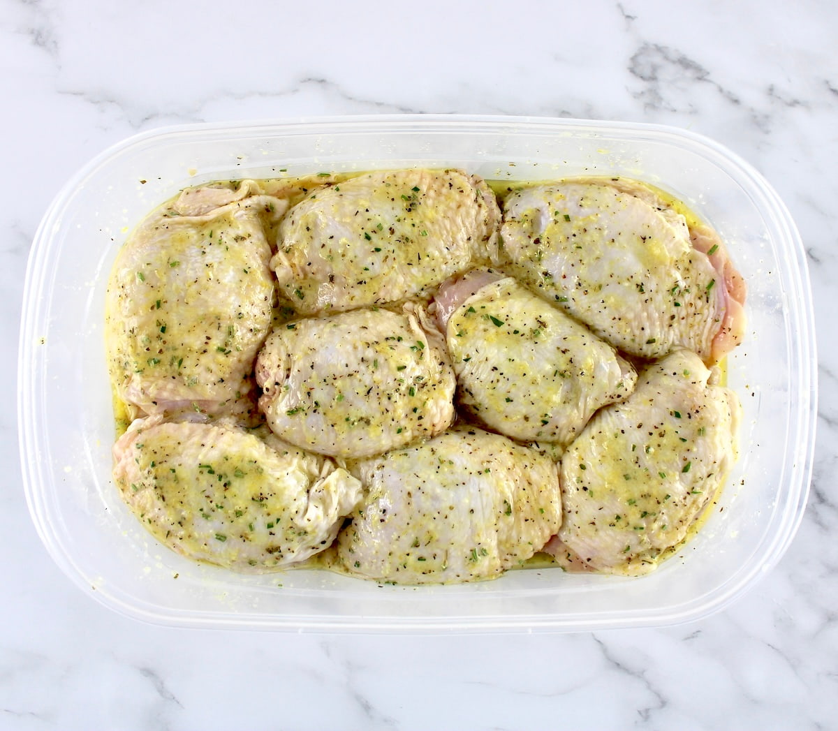 8 chicken thighs with marinade in rectangular food storage container