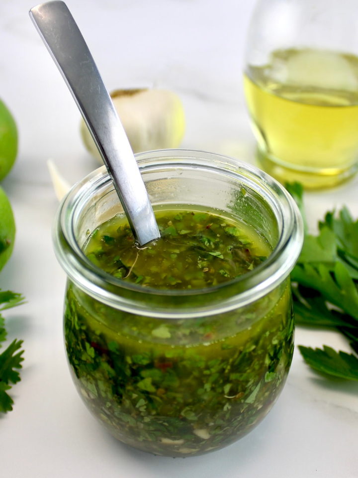 Chimichurri Sauce in open glass jar with spoon