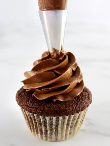 Keto Chocolate Frosting being piped onto a chocolate cupcake