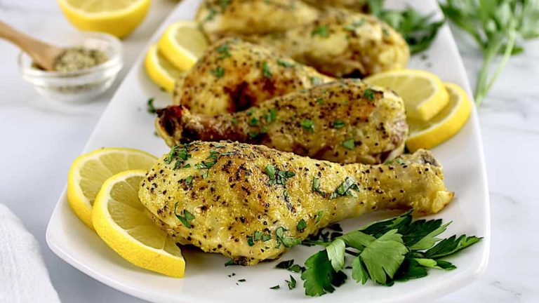 lemon pepper chicken drumsticks on white plate with lemon slices and parsley garnish