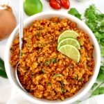 Mexican Cauliflower Rice in white bowl with spoon and 3 lime slices on top