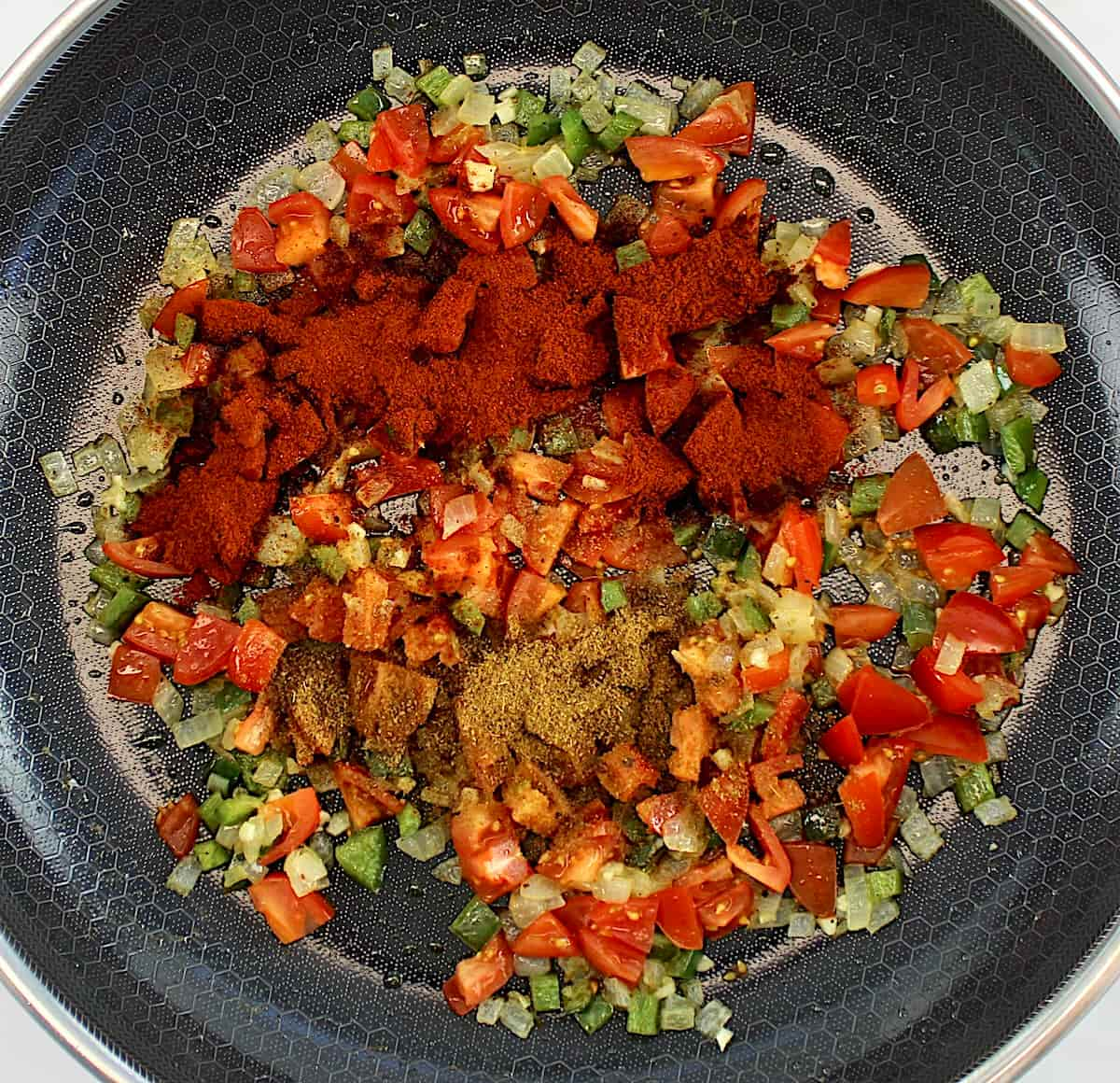 diced onions, tomatoes and jalapeño peppers in skillet with spices