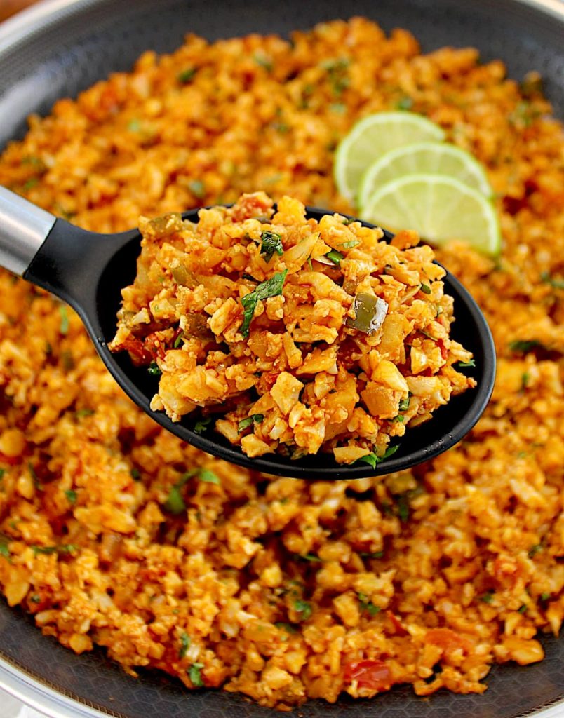 closeup of Mexican Cauliflower Rice in black serving spoon held up over skillet