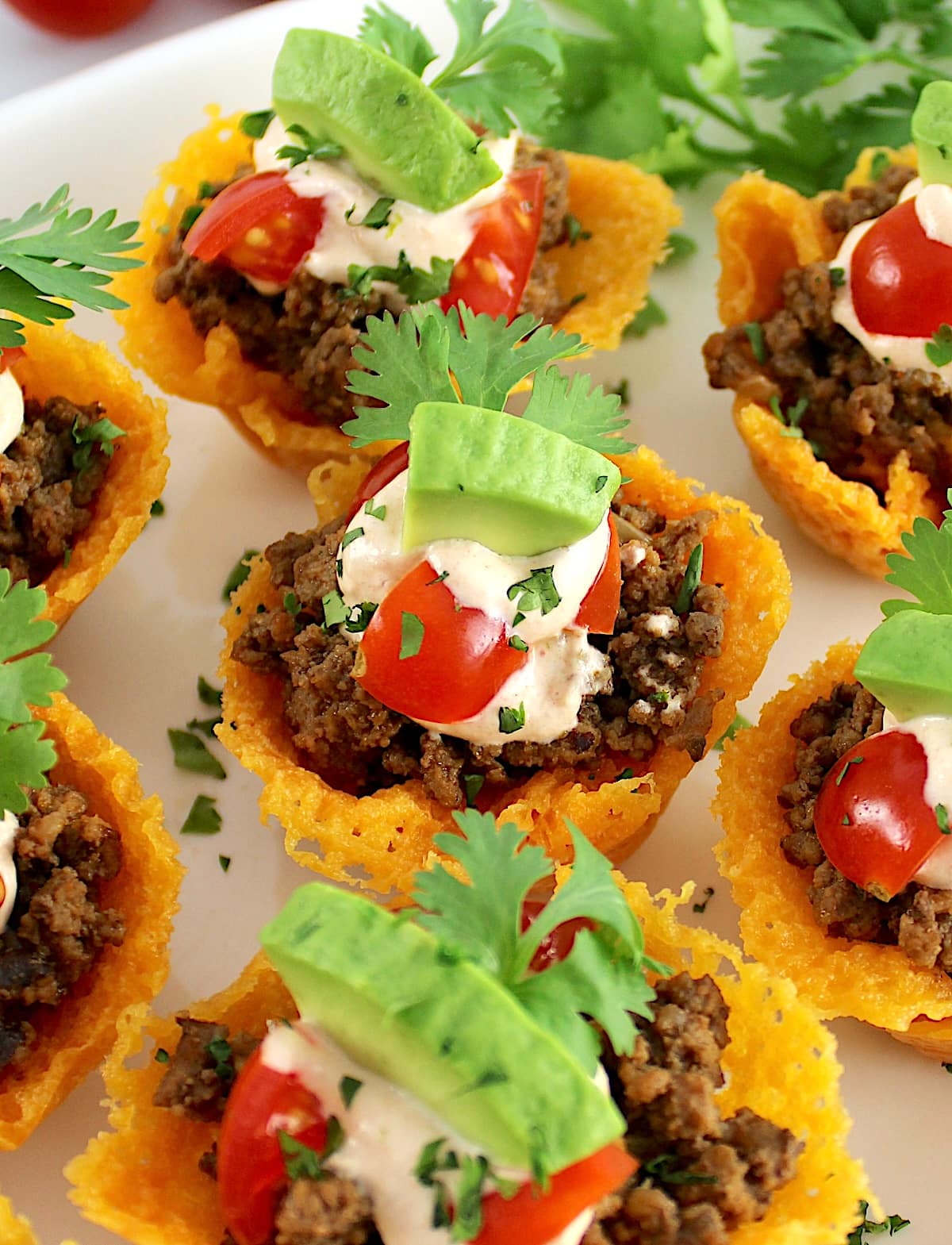 closeup of Mini Taco Bites on white platter with avocado piece on top