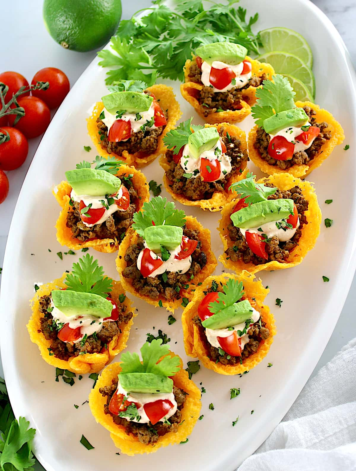 overhead view of Mini Taco Bites on white oval platter with tomatoes in back