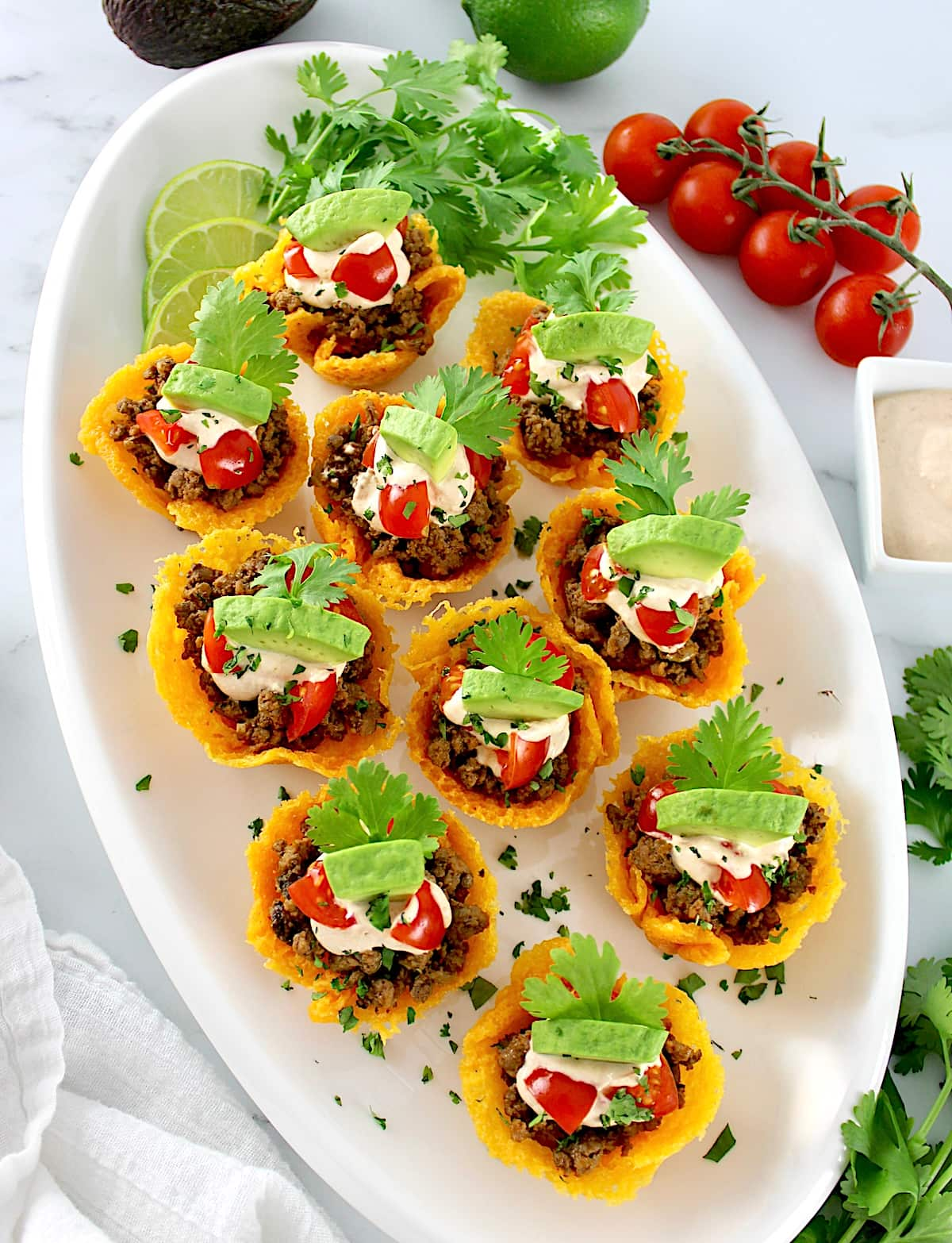 overhead view of Mini Taco Bites on white oval platter with tomatoes in back