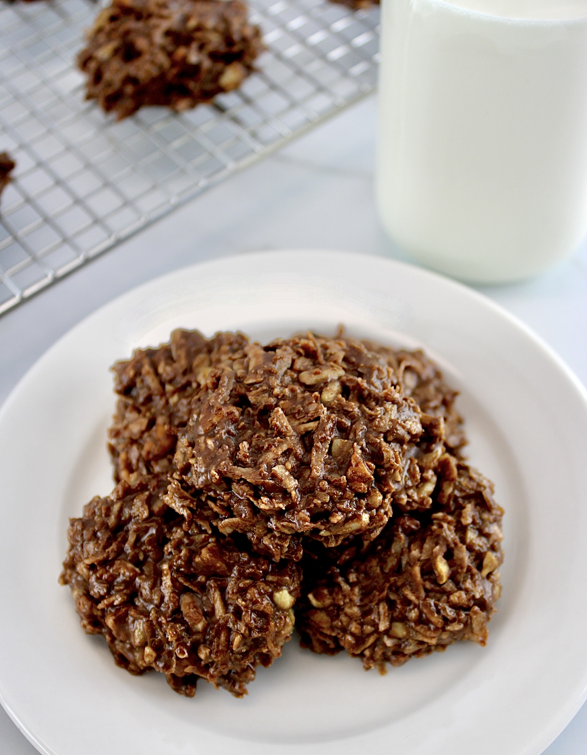 No-Bake Keto Cookies on white round plate with glass milk bottle in back