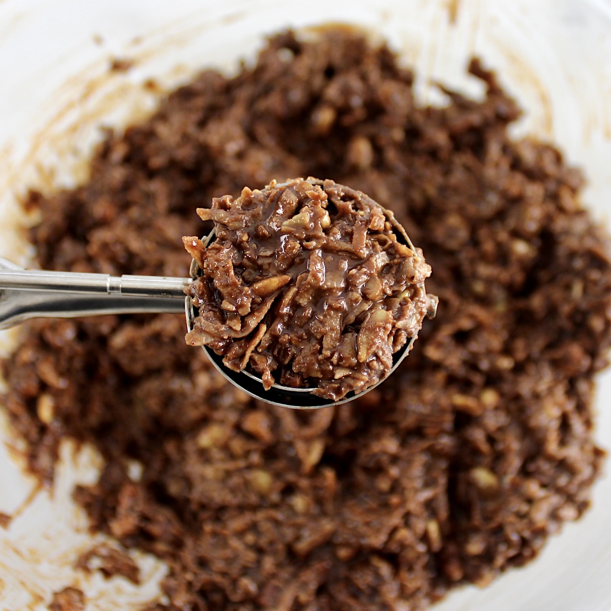 No-Bake Keto Cookie dough in cookie scooper held over glass bowl