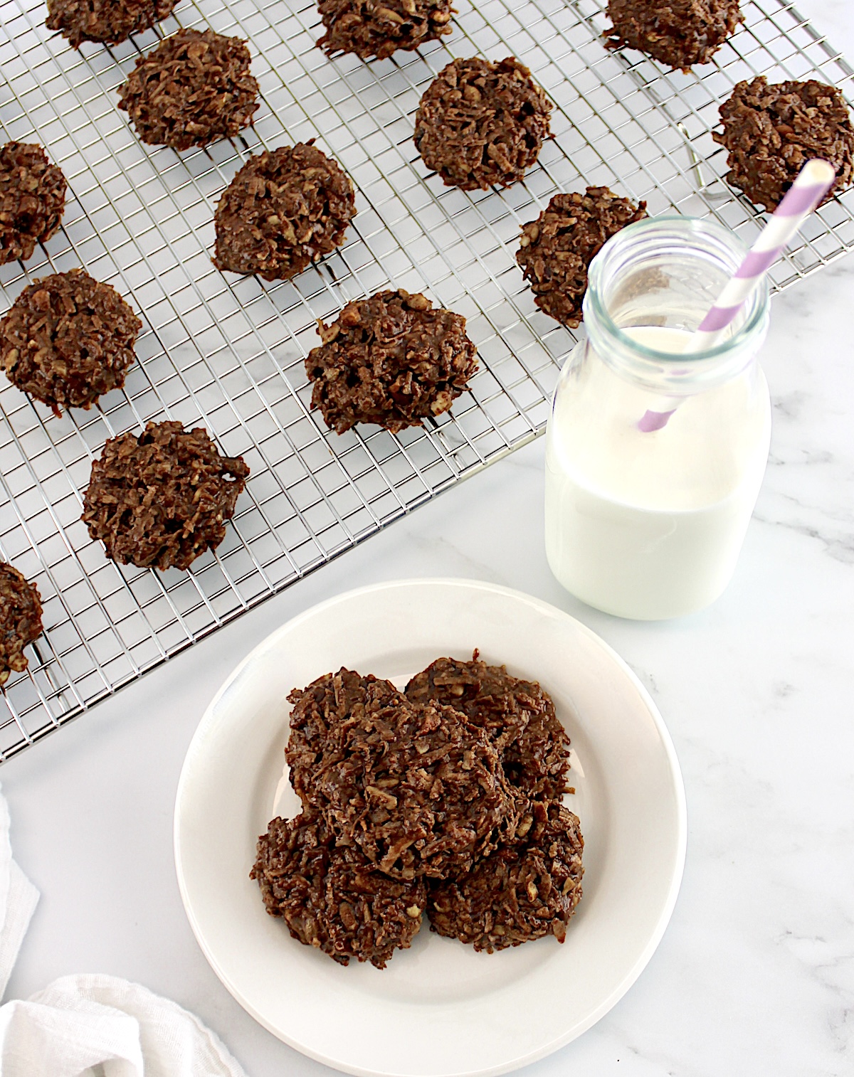 No-Bake Keto Cookies on white round plate with glass milk bottle in back