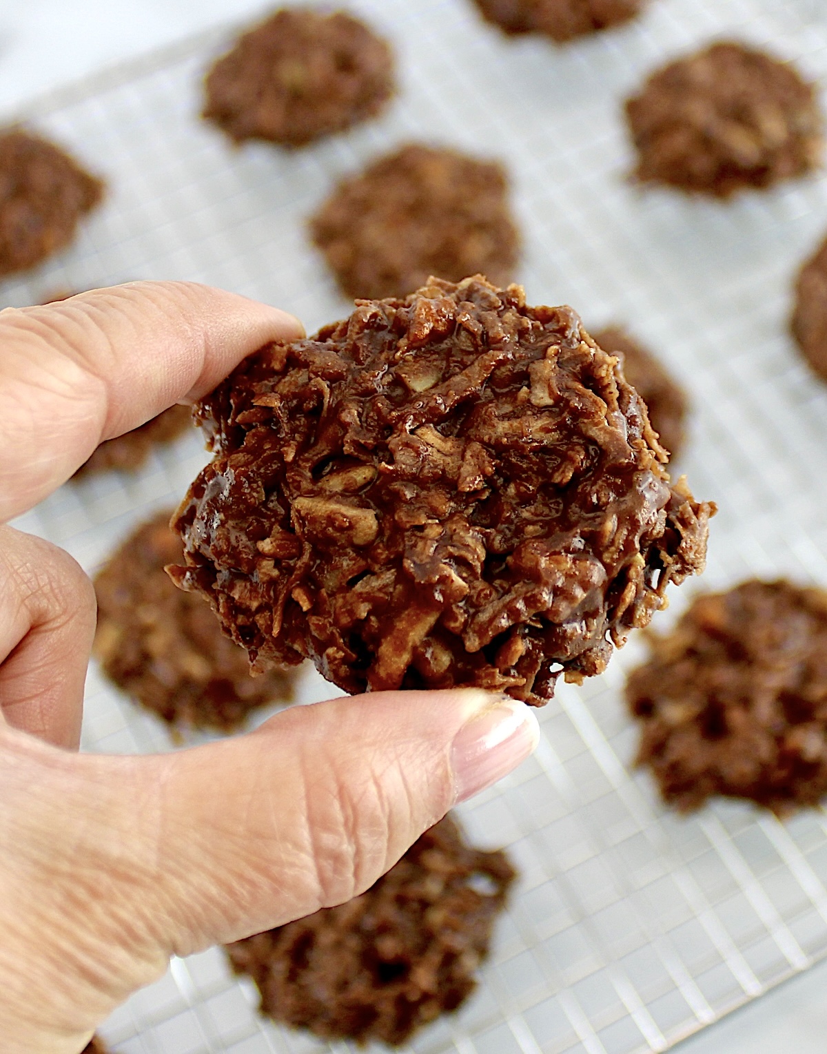 holding up No-Bake Keto Cookie with cooling rack in back