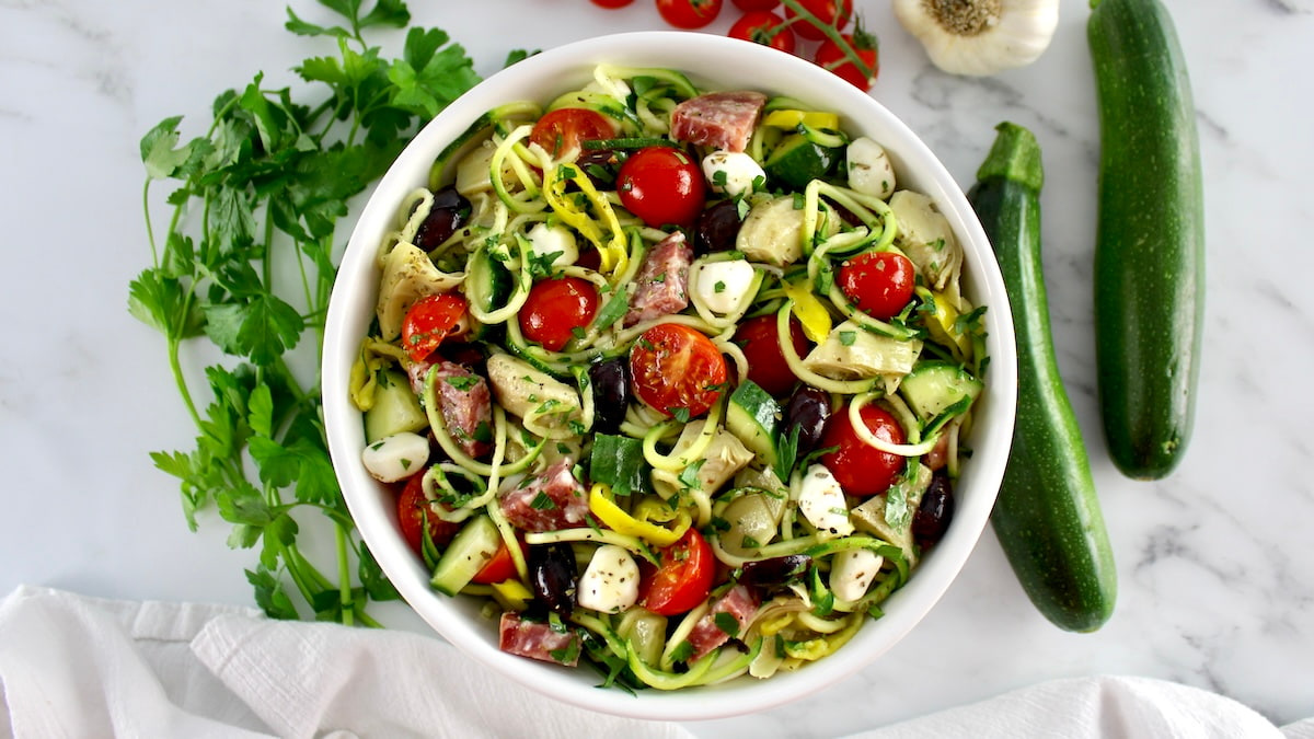 overhead view of Zucchini Noodle Pasta Salad in white bowl with veggies around