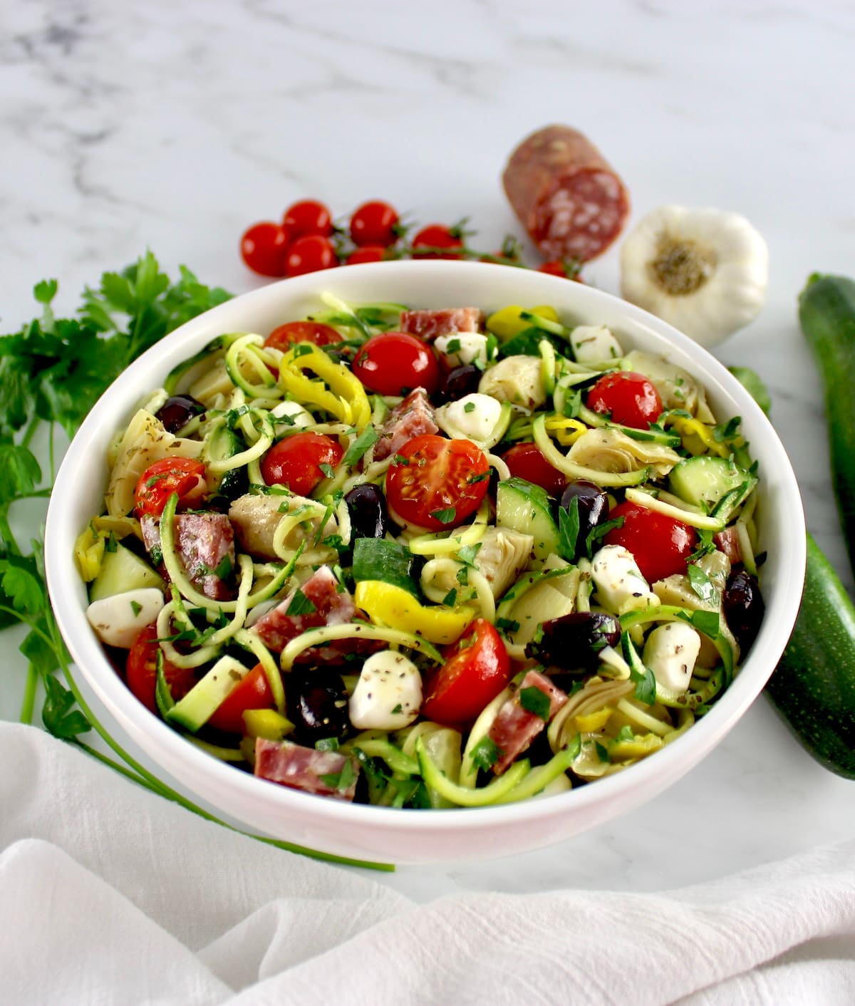 Zucchini Noodle Pasta Salad in white bowl with fresh veggies around