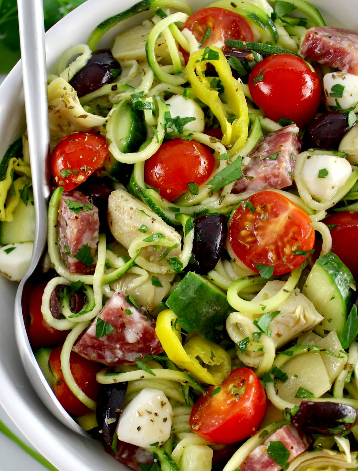 Zucchini Noodle Pasta Salad in white bowl with silver spoon