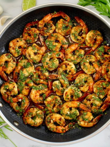 Chimichurri Shrimp in skillet with herbs around