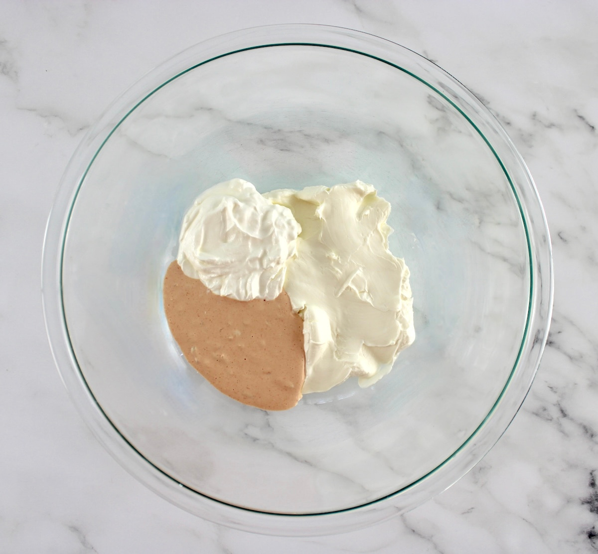 Reuben dressing, cream cheese and sour cream in glass bowl unmixed