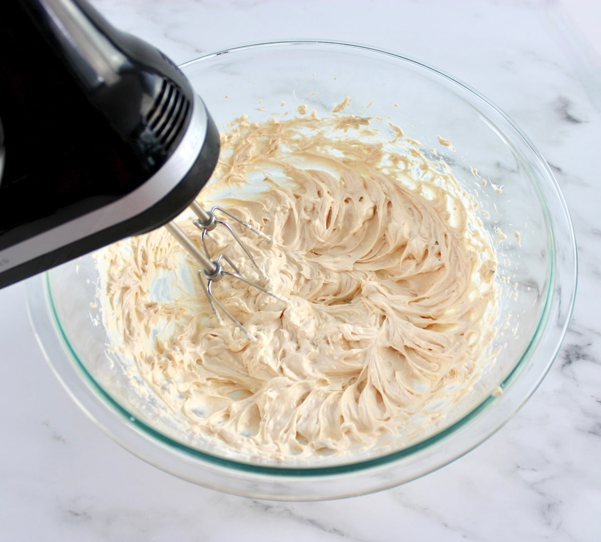 Hot Reuben Dip dressing in glass bowl being mixed with hand mixer