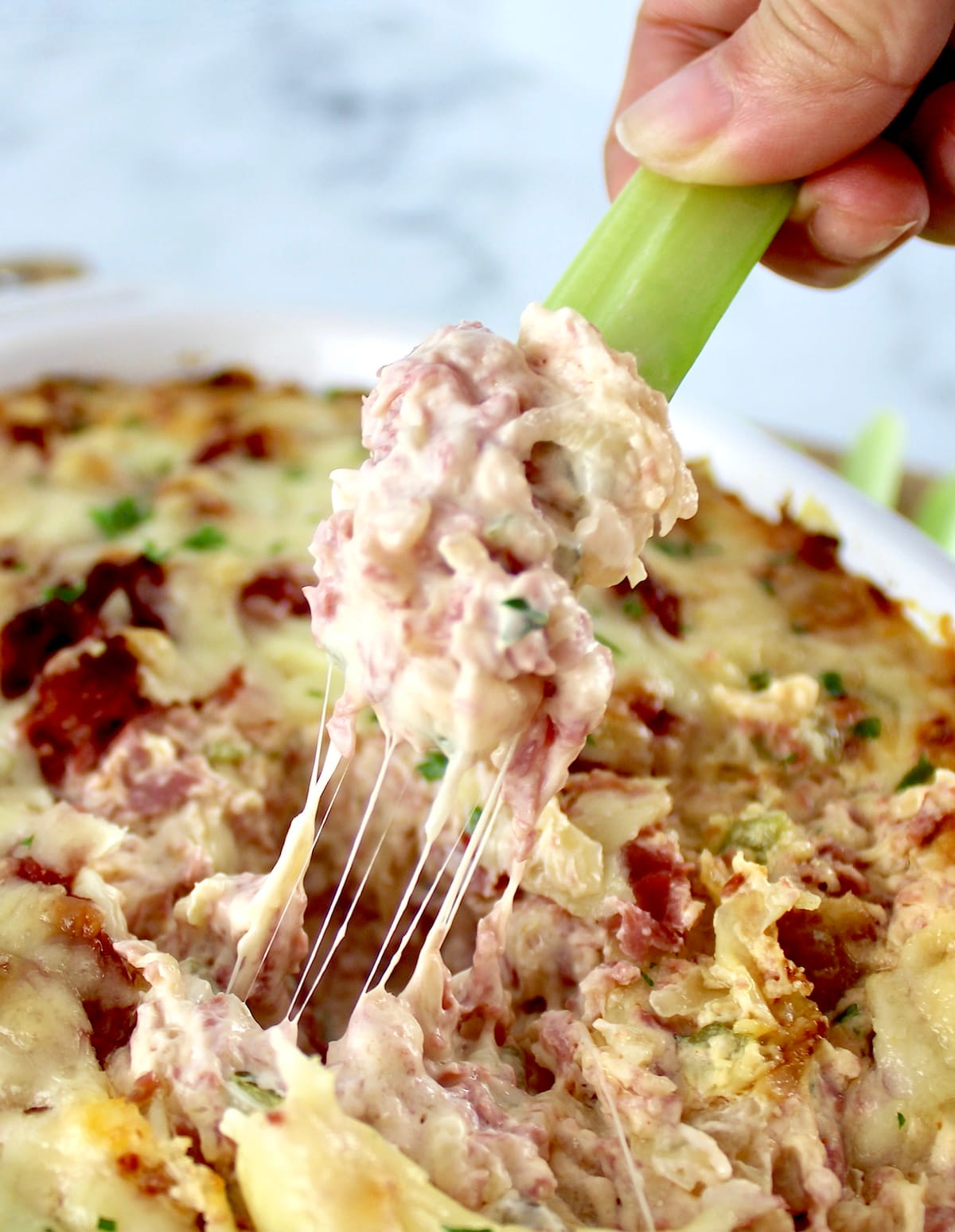 Hot Reuben Dip being dipped with celery stick