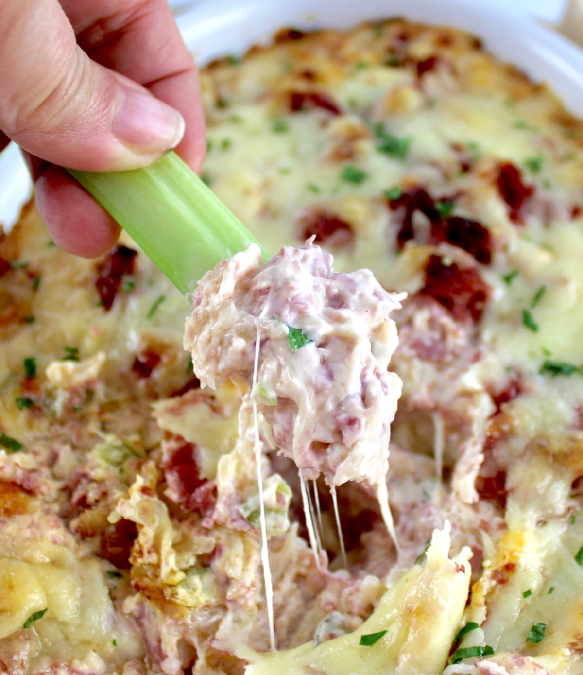 Hot Reuben Dip being dipped with celery stick