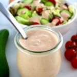 Keto Russian Dressing in open glass jar with spoon and salad in back