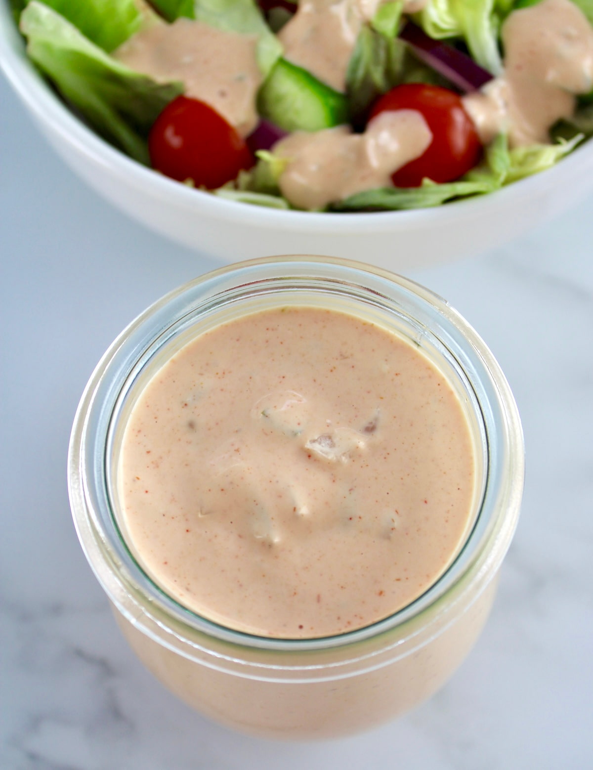 overhead view of Keto Russian Dressing in open glass jar with salad in back