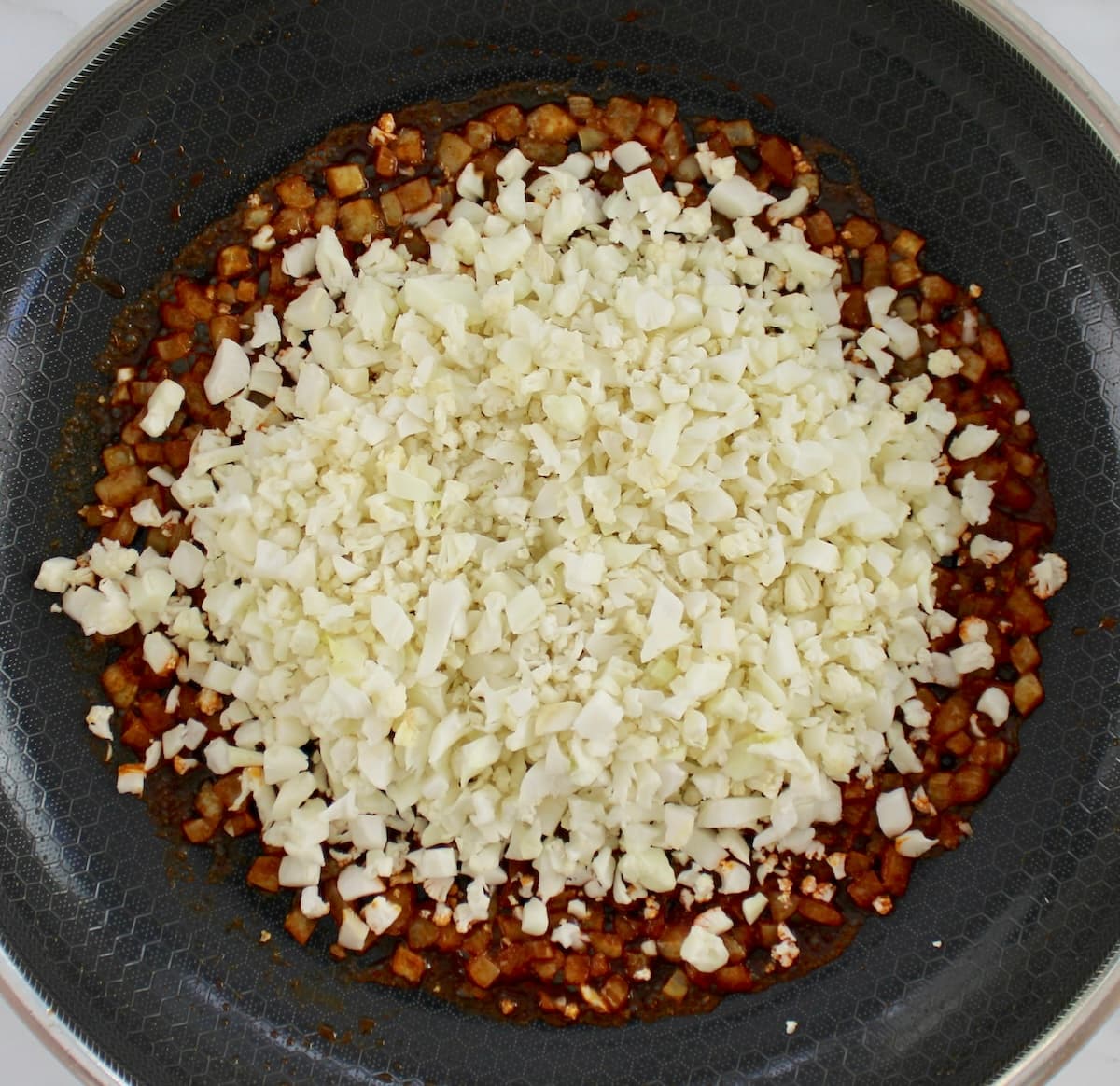 cauliflower rice in skillet with spices and onions