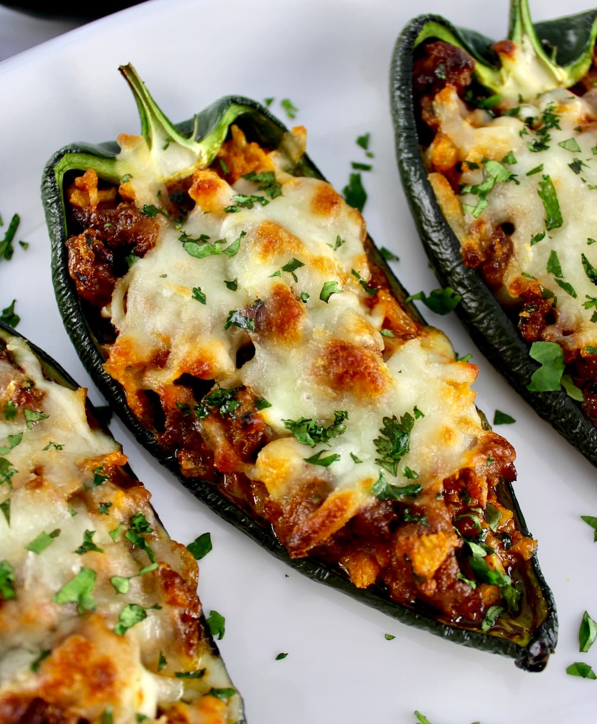 closeup of Stuffed Poblano Peppers on white plate with chopped cilantro