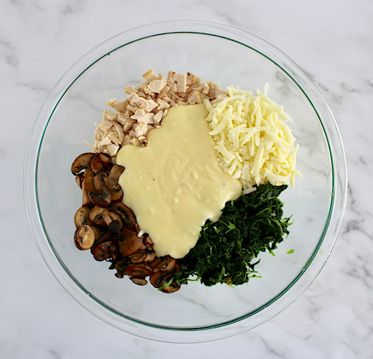 cooked mushrooms, chopped chicken, alfredo sauce, spinach and mozzarella cheese in glass bowl in groups unmixed