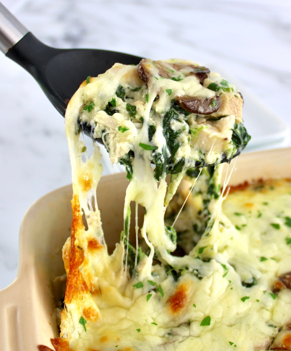 Chicken Alfredo Casserole being scooped out of casserole dish