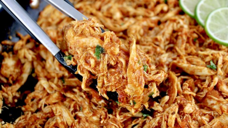 closeup of tongs holding up Chicken Tinga