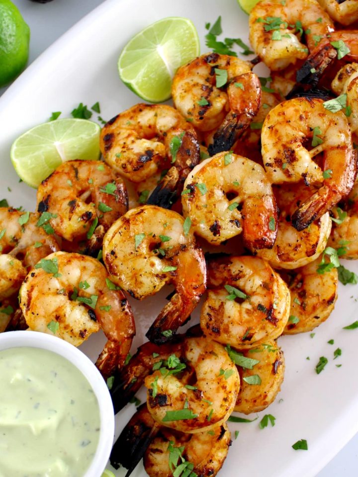 Grilled Lime Cilantro Shrimp Skewers on white oval platter with avocado ranch sauce on side