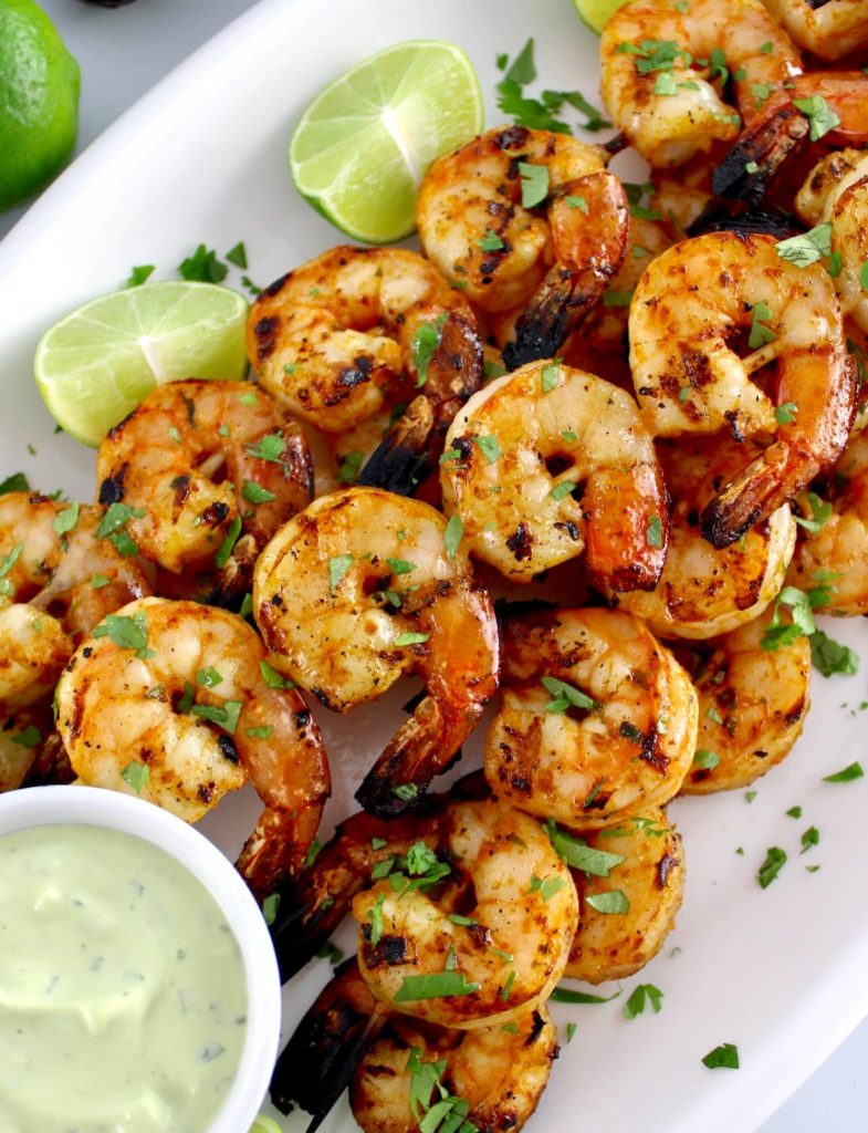 Grilled Lime Cilantro Shrimp Skewers on white oval platter with avocado ranch sauce on side