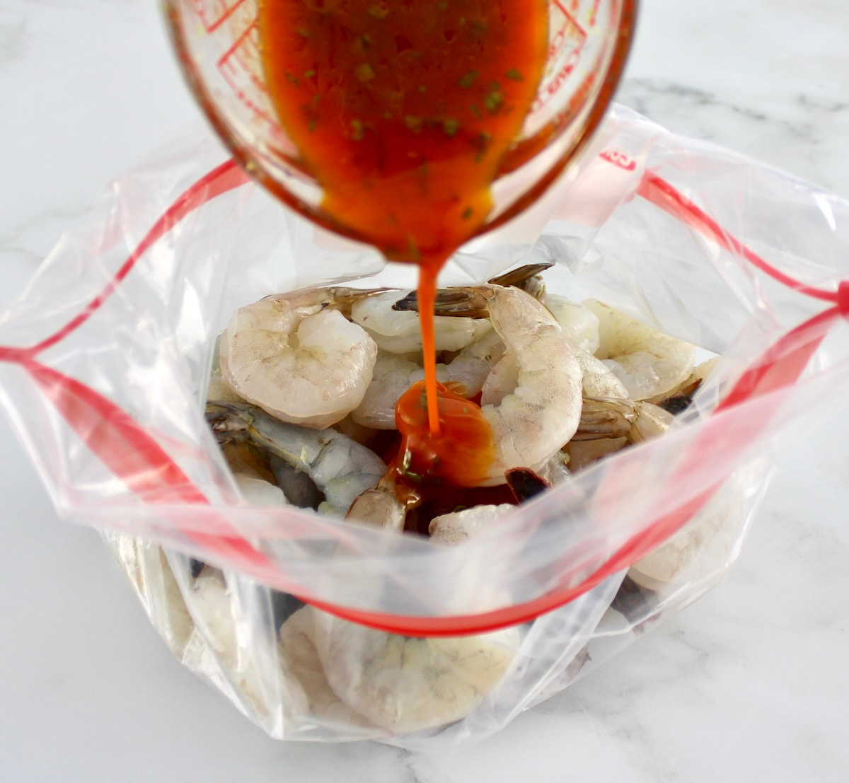 lime cilantro marinade being poured over shrimp in food storage bag