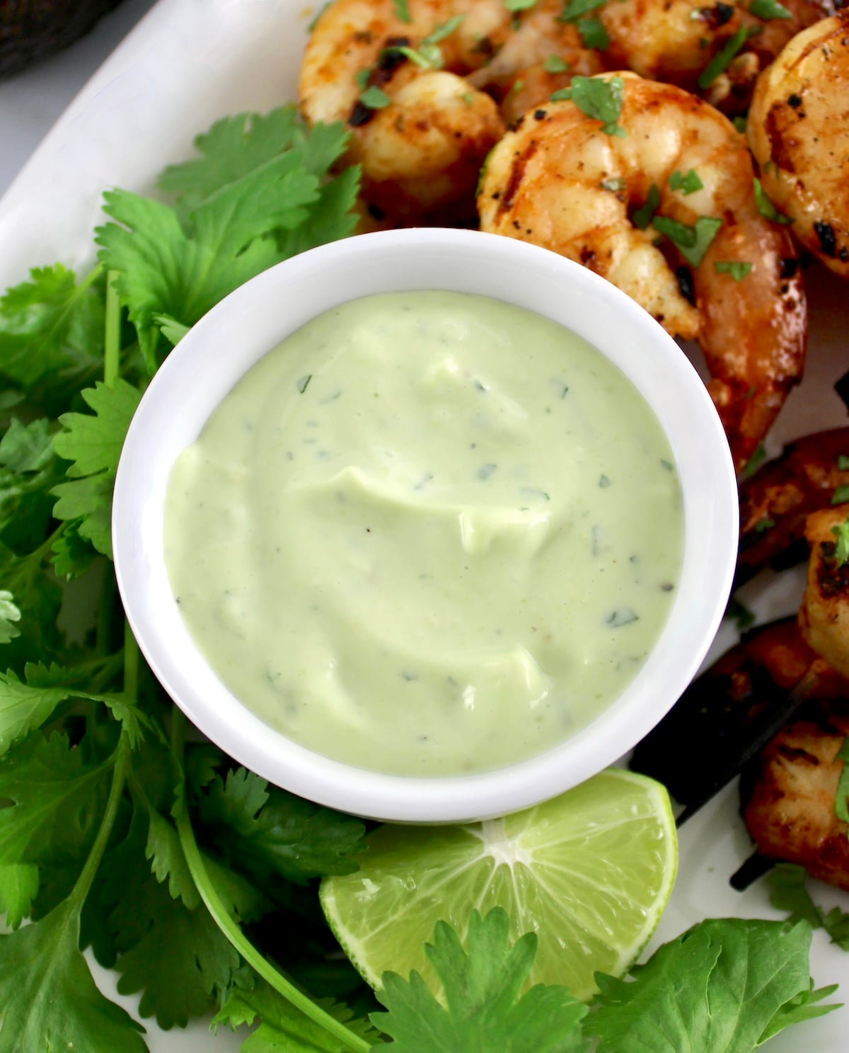 avocado ranch in white bowl with shrimp and cilantro in back