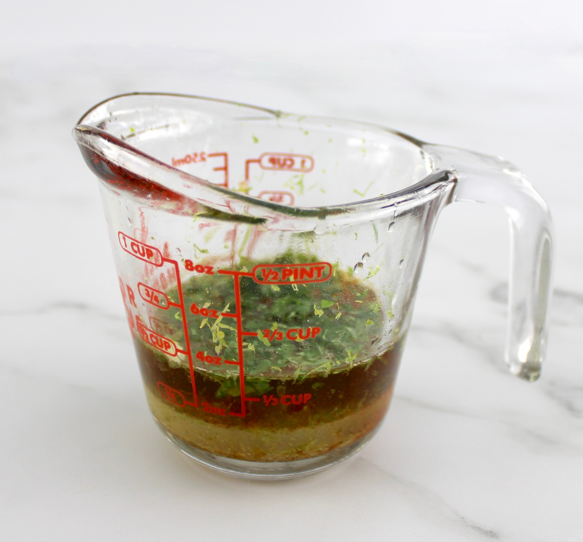 measuring cup with lime cilantro marinade ingredients unmixed