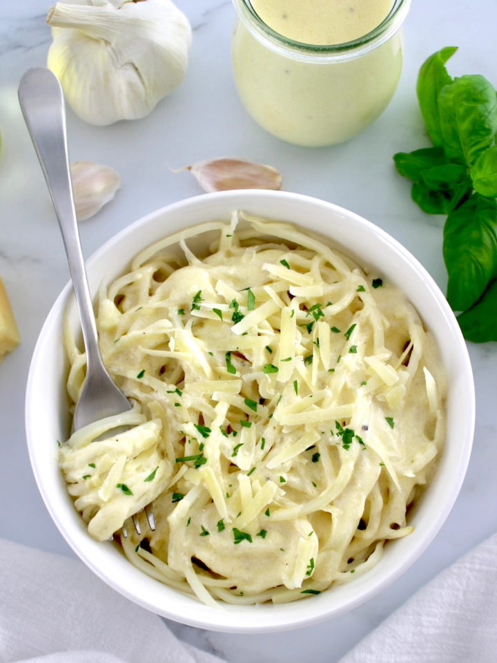 Keto Alfredo Sauce over palmini in white bowl with fork