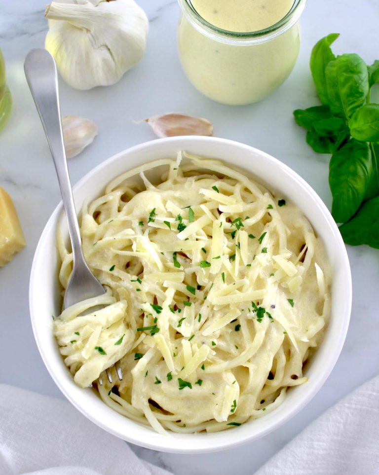 Keto Alfredo Sauce over palmini in white bowl with fork