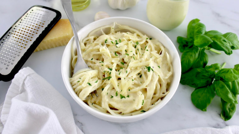 Keto Alfredo Sauce over palmini in white bowl with fork