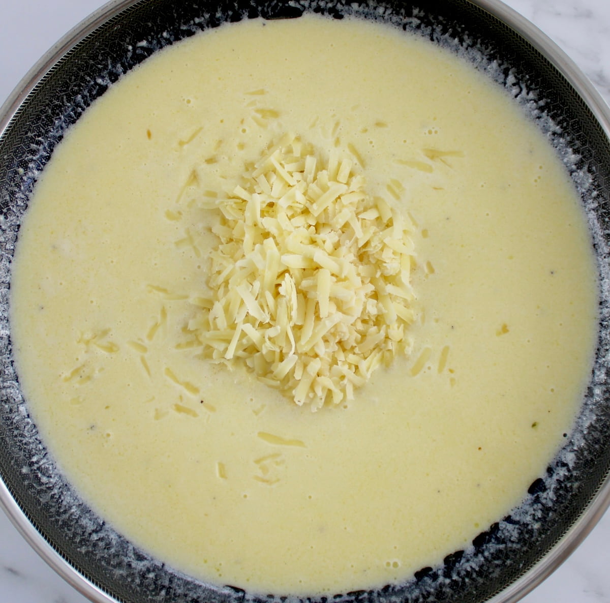 alfredo sauce in skillet with grated parmesan cheese