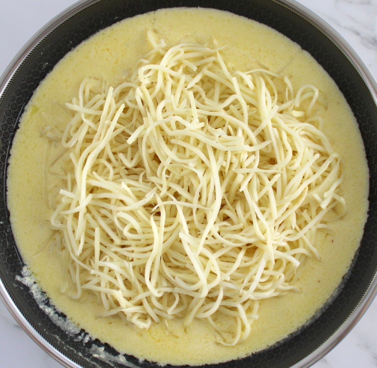 Keto Alfredo sauce in skillet with palmini noodles on top