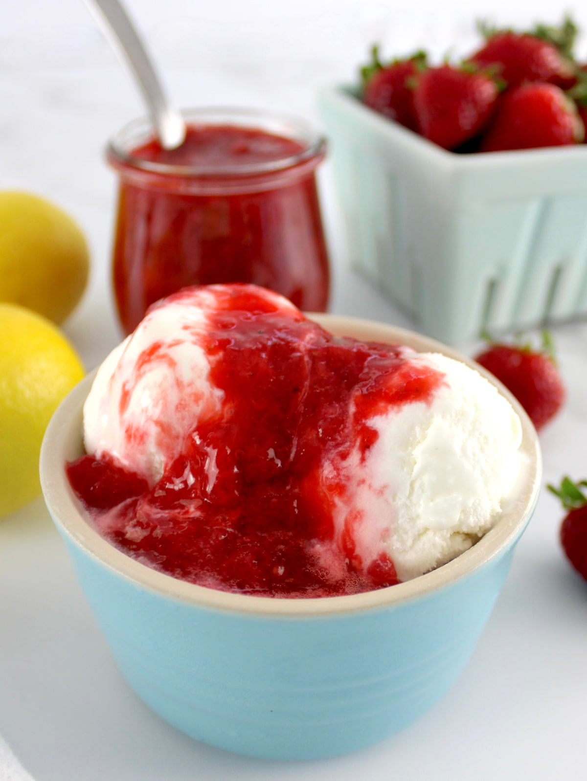 closeup of vanilla ice cream in blue bowl with Keto Strawberry Sauce on top
