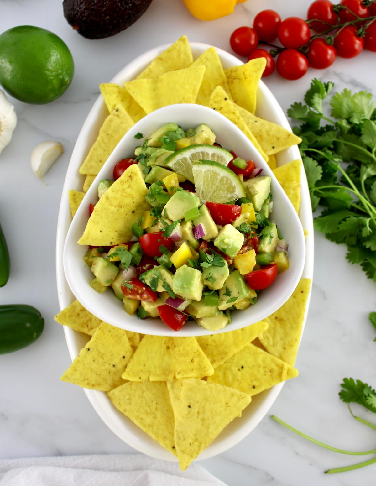 overhead view of Avocado Salsa in white bowl with tortilla chips around