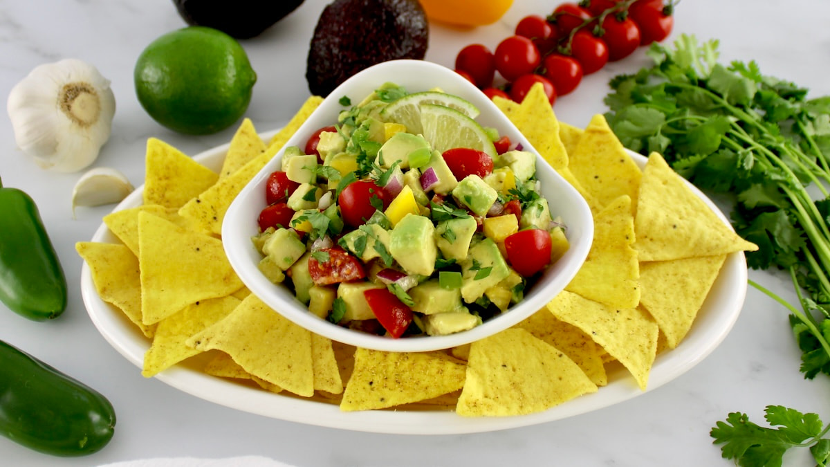 Avocado Salsa in white bowl with tortilla chips around