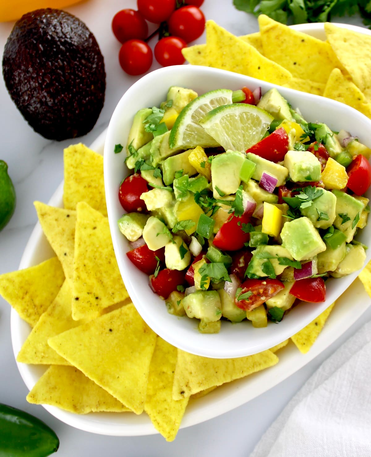 Avocado Salsa in white bowl with tortilla chips around