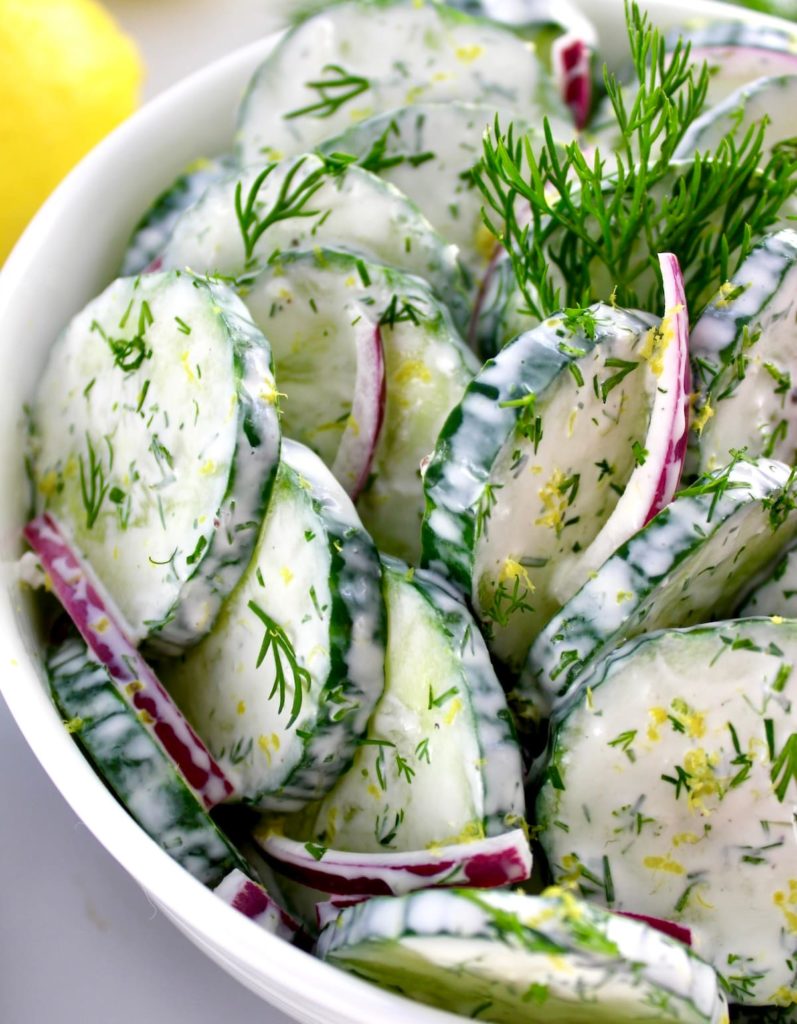 closeup of Creamy Cucumber Salad in white bowl with fresh dill