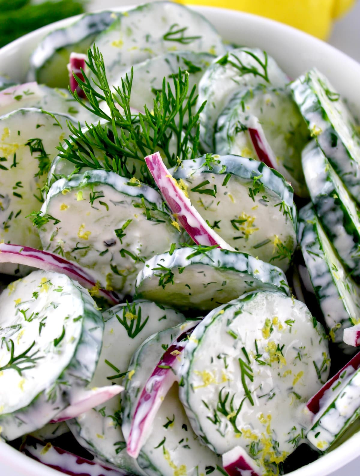 closeup of Creamy Cucumber Salad in white bowl with fresh dill