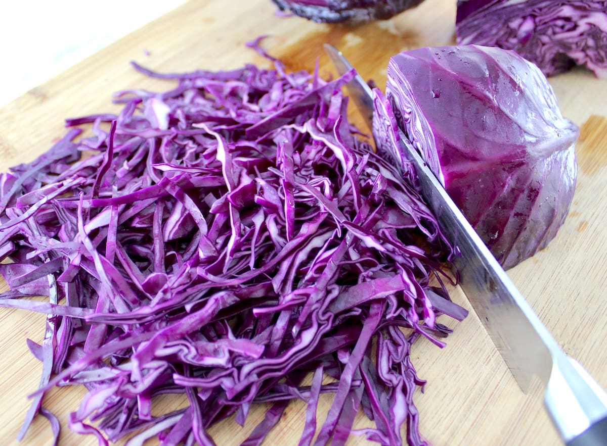 shredded red cabbage on cutting board with knife