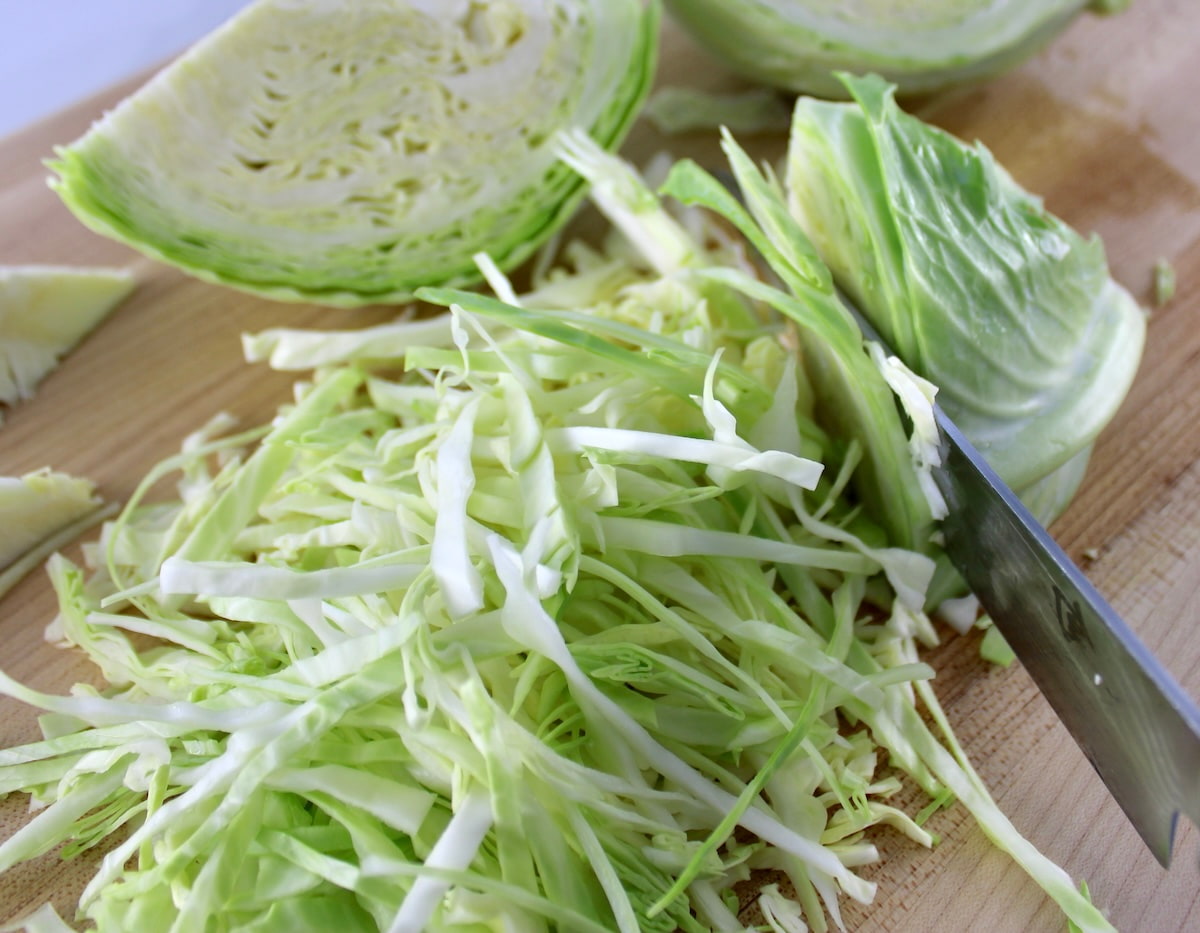 shredded cabbage on cutting board with knife